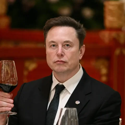 Elon Musk tenant une verre de vin dans un restaurant.