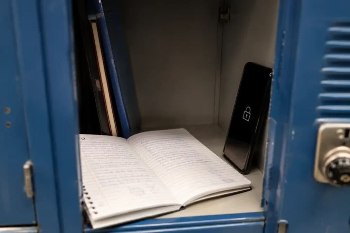 Cahier d'écolier ouvert près d'un téléphone verrouillé dans un casier scolaire