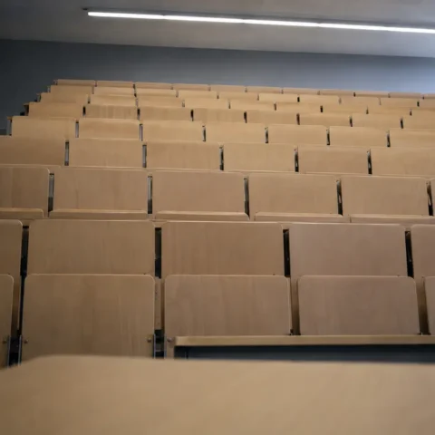 Amphithéâtre universitaire vide vu depuis l'estrade, rangées de sièges en gradins