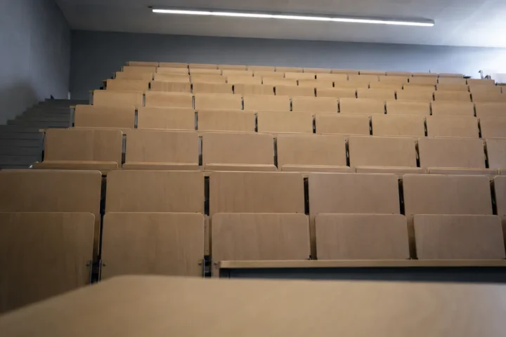 Amphithéâtre universitaire vide vu depuis l'estrade, rangées de sièges en gradins