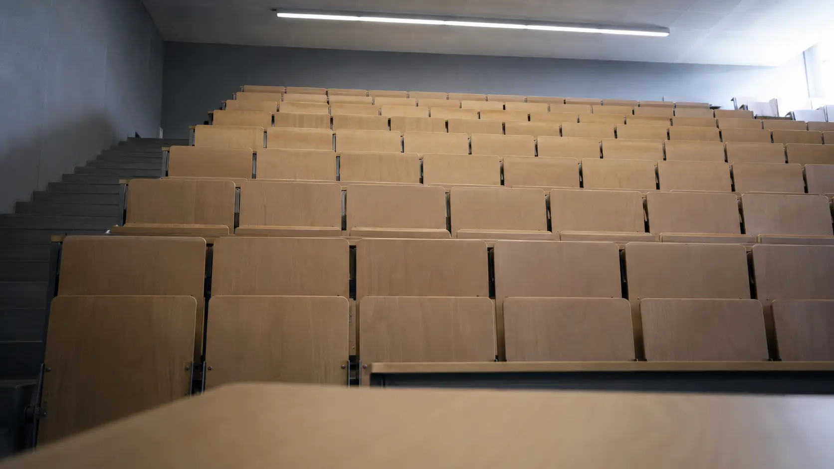 Amphithéâtre universitaire vide vu depuis l'estrade, rangées de sièges en gradins