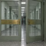 Deux portes battantes vitrées dans un corridor institutionnel vide