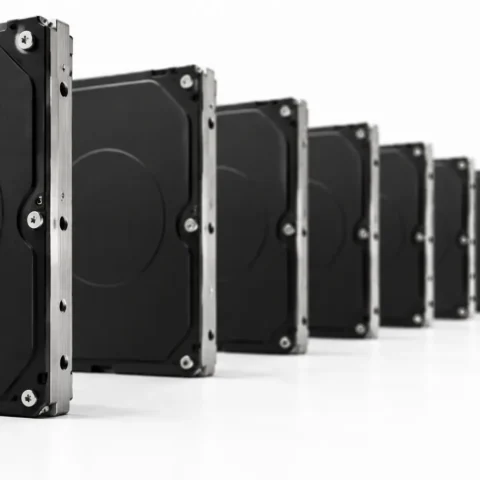 Longue rangée de disques durs noirs identiques alignés sur une surface blanche