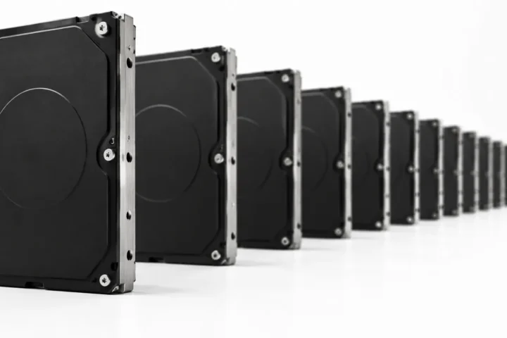 Longue rangée de disques durs noirs identiques alignés sur une surface blanche