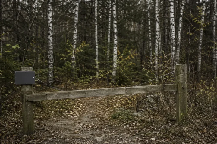 Barrière de bois et câble fermant l'entrée d'un sentier forestier