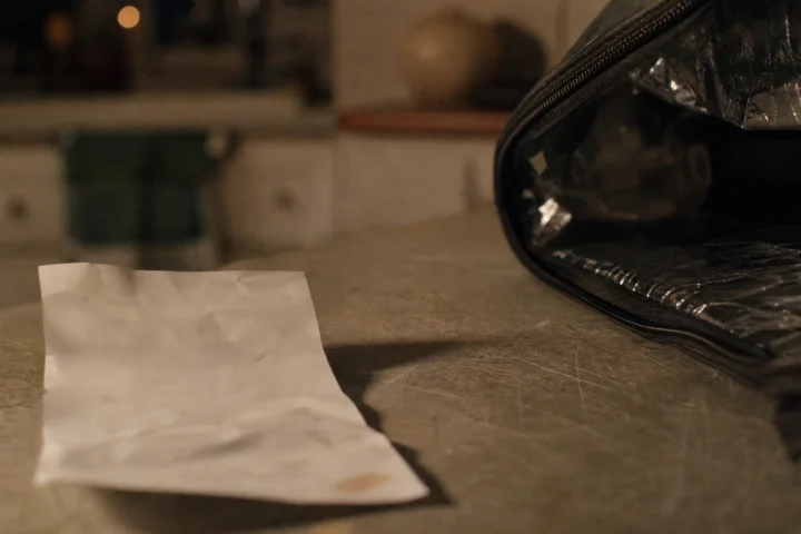 Reçu froissé posé sur un comptoir de cuisine à côté d'un sac de livraison isotherme