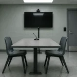Salle vide de contrôle des motifs de détention, avec un écran de visioconférence éteint et une porte d'acier verrouillée.