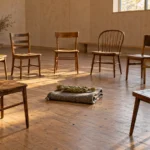 Cercle de chaises de bois vides dans une salle communautaire éclairée par une fenêtre haute