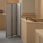 Barre des témoins vide et paravent entrouvert dans une salle d’audience
