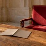 Livret refermé et chaise reculée devant une table dans une salle vide