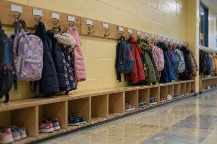 Deux crochets vides au milieu d'une rangée de manteaux dans un vestiaire d'école primaire