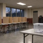 Isoloirs en carton et urne scellée dans une salle syndicale vide